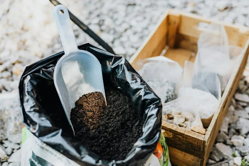 Düngesubstrat und Gartenschaufel neben einem Kasten mit organischen Düngern