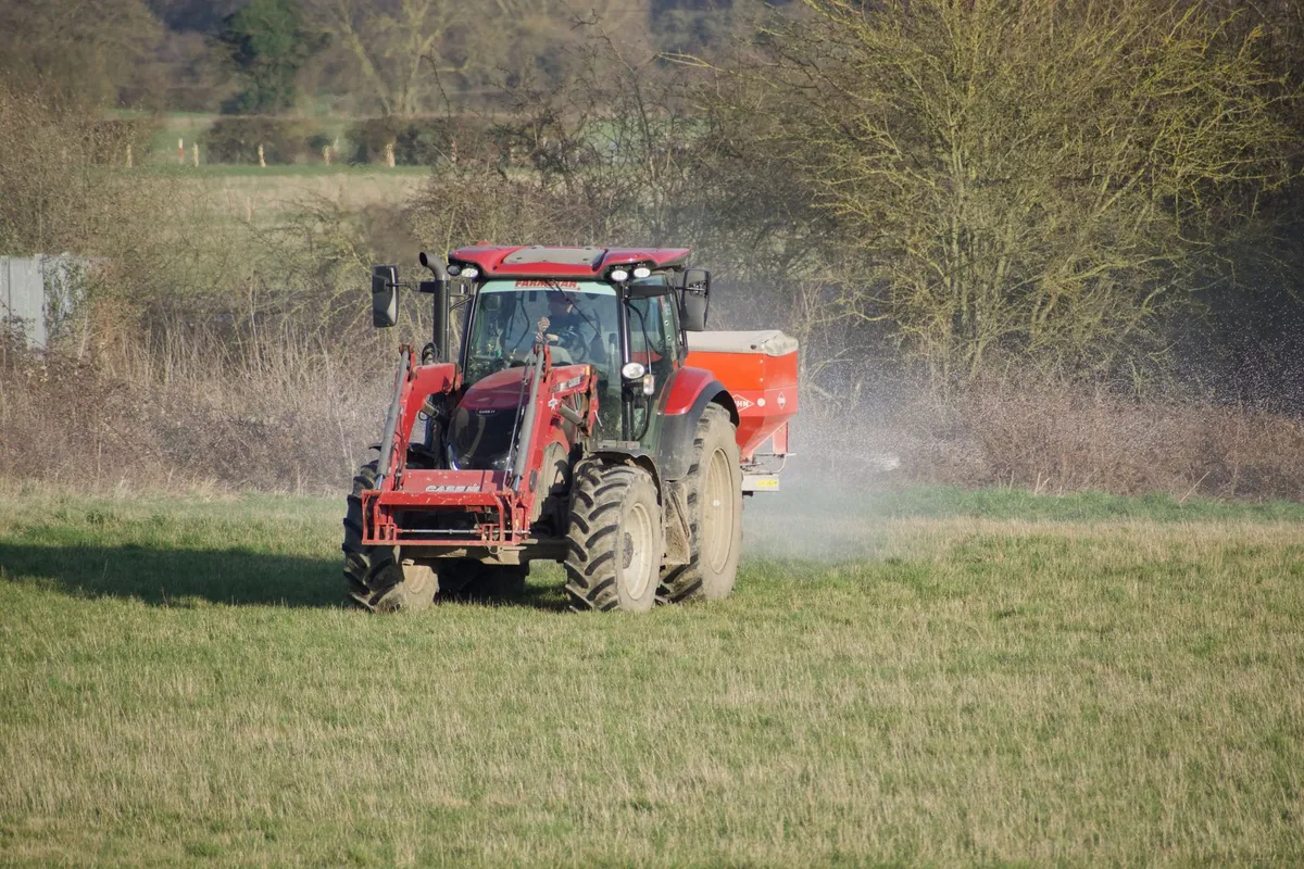Ein Streuwagen gefüllt mit Rasensamen steht auf einer vorbereiteten Fläche im Garten.